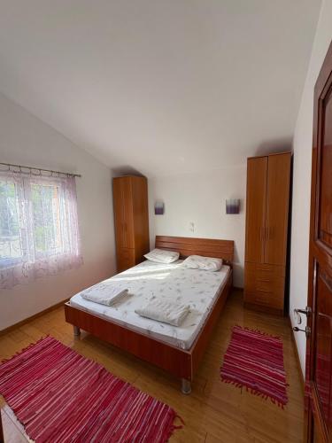a bedroom with a bed and two rugs at Apartments Ćuković in Risan