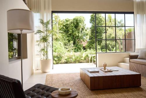 a living room with a coffee table and a large window at The Young Villas Tropical Villas in Seseh in Canggu