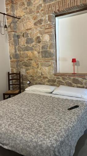 a bed in a room with a stone wall at Fattoria solidale del Circeo in Pontinia