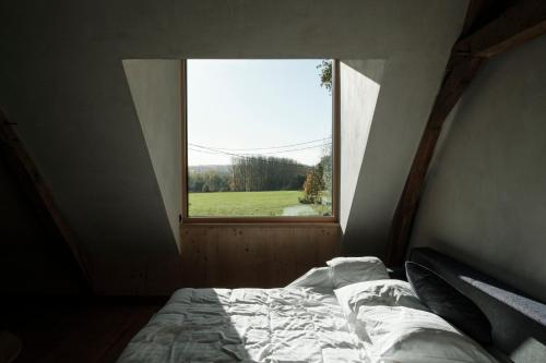 a bed in a room with a large window at Sualma in Zwalm