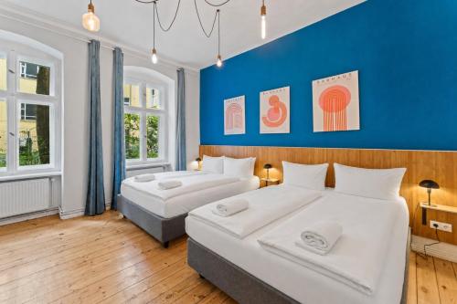 two beds in a room with a blue wall at primeflats - Apartments Genter Berlin-Wedding in Berlin
