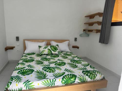 a bed with a green and white comforter and pillows at Maison Mimosa in Grand-Bassam