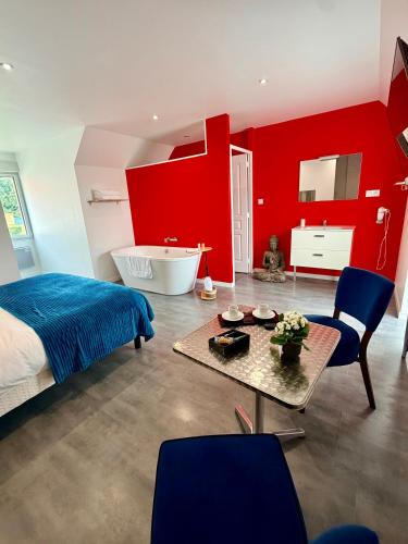 a bedroom with red walls and a bed and a table at Aux Charmes - Suites Prestige et Petit Déjeuner en chambre - Cote d Opale in Isques