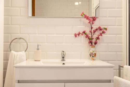ein Waschbecken im Badezimmer mit einer Vase mit Blumen darin in der Unterkunft Casa do Armando in Achadinha