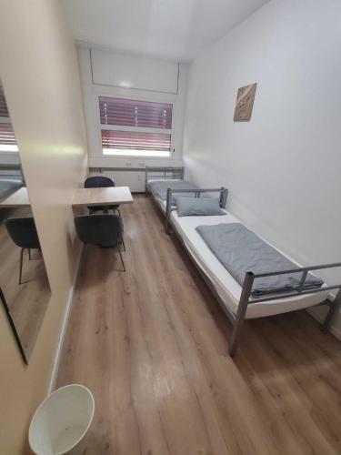 a room with two beds and a desk and a table at Sitya Hostel München in Munich