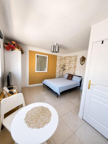a bedroom with a bed and a table and a room at Cannes Centre Studio Lumineux et Chic, à 9 Min à Pied du Palais des Festivals et des Plages, Clim in Cannes