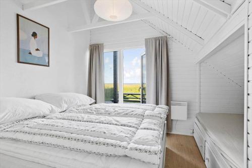 a white bedroom with a bed and a window at LN2067-Hjorring-Gabet-7 in Lønstrup