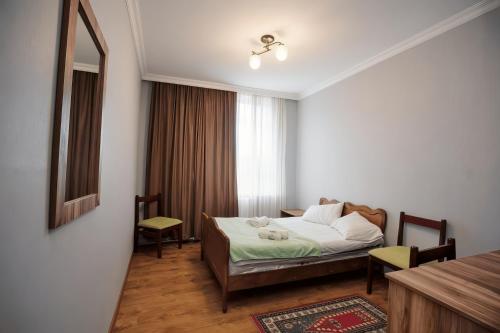 a bedroom with a bed and a table and a window at Hotel Nikea Paradiso in Kutaisi