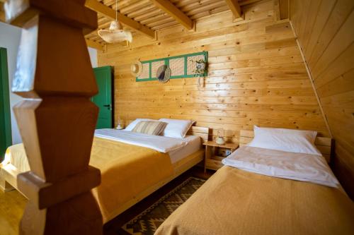 two beds in a room with wooden walls at DejaView Cabin&Camp in Rogojel