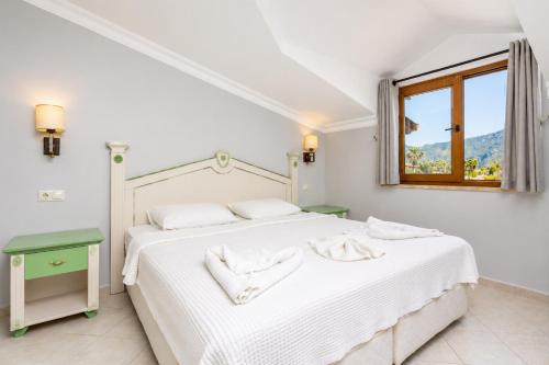 a white bedroom with a white bed and a window at Villa Aysel Paradise in Dalyan