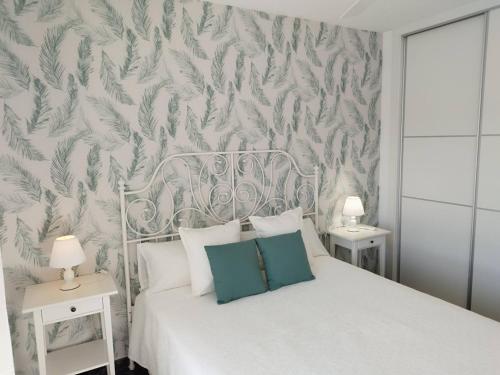 a bedroom with a white bed with a green and white wallpaper at Apartamento Ferrara in Torrox Costa