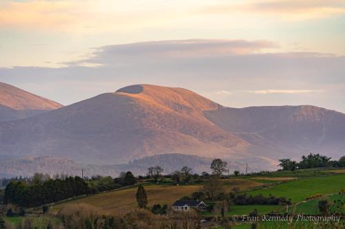a view of a mountain with a house in a field at Panorama Peace Nature in Castlewellan