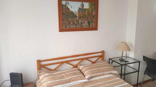 a bed in a room with a picture on the wall at Depto Brown in Mar del Plata