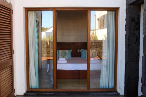 a room with a bed through a glass door at Baia da Barca in Madalena
