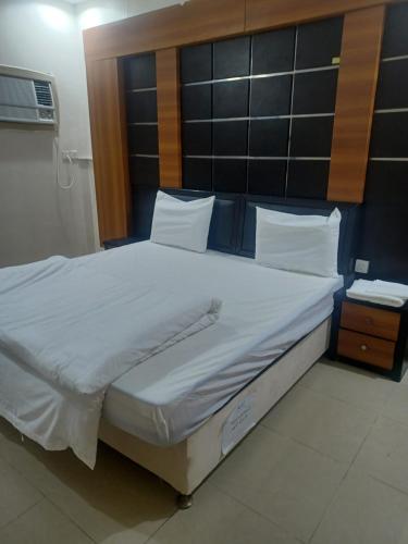 a large bed with white sheets and a wooden headboard at مؤسسة علي عايض سداح الدوسري للمقاولات in Abu Arish