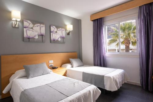 a hotel room with two beds and a window at Ona el Marqués in Puerto de Santiago