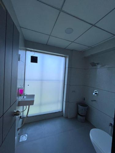 a bathroom with a window and a toilet and a sink at Hotel 7 Square in Surat