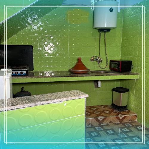a green kitchen with a counter and a microwave at Auberge Bab chellalat in Tamarout