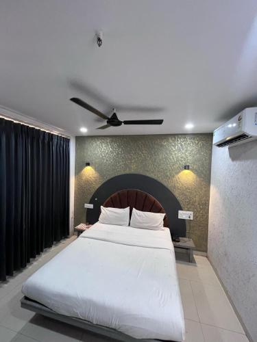 a bedroom with a large white bed with a ceiling at Hotel 7 Square in Surat