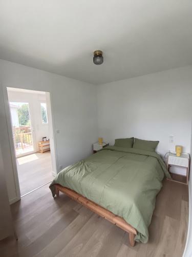 a bedroom with a bed with a green comforter at Appartement Neuf avec Balcon in Hendaye