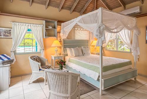 a bedroom with a bed and two chairs and windows at Titi Vacation Homes in Cobbs Cross