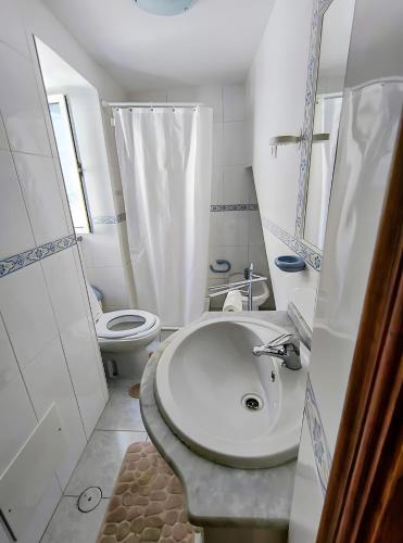 a white bathroom with a sink and a toilet at Refúgio do Xekeraute in Piódão