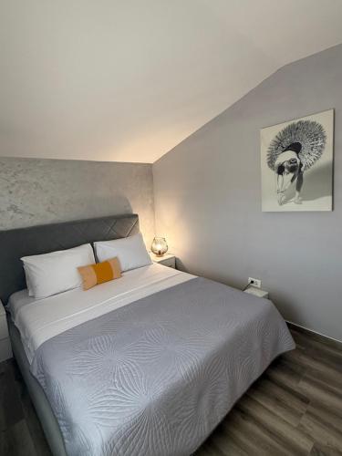 a bedroom with a white bed and a picture on the wall at Apartmani Stijepovic in Podgorica