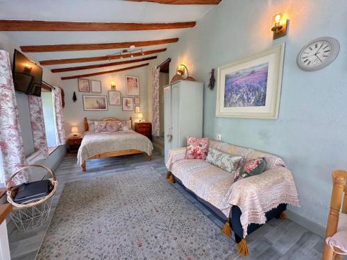 a bedroom with a couch and a bed and a clock at La Colline de Tilleul - Les Deux Puits - Cosy Cottage with swimming pool near Aubeterre in Saint-Romain