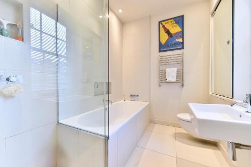a white bathroom with a tub and a sink at Elegant 3 bed apt with rooftop terrace in Pimlico in London
