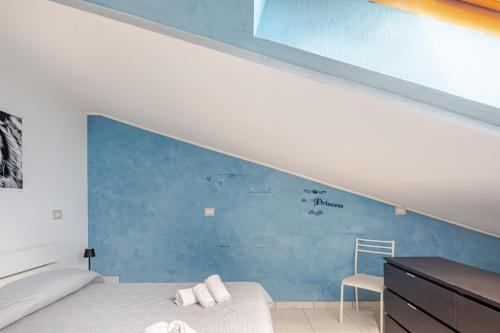 a bedroom with a blue wall with a bed and a chair at The Lake View - Terrazza Panoramica Vista Lago in Marta