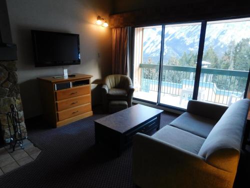 a living room with a couch and a large window at Douglas Fir Resort & Chalets in Banff