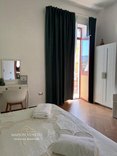 a bedroom with a bed and a desk and a window at Maison Veneto Vesuvius Rooftop in Torre Annunziata