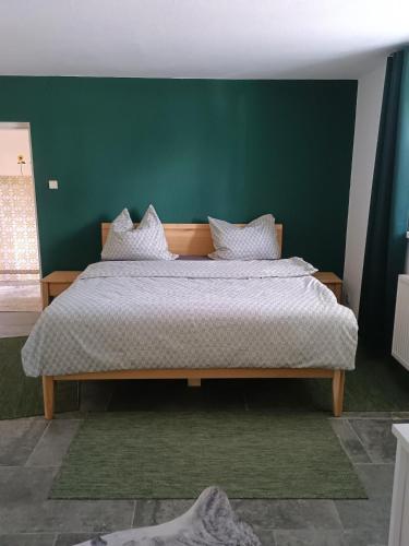 a bedroom with a large bed with a green wall at Ferienhaus Strohmayer in Schweiggers