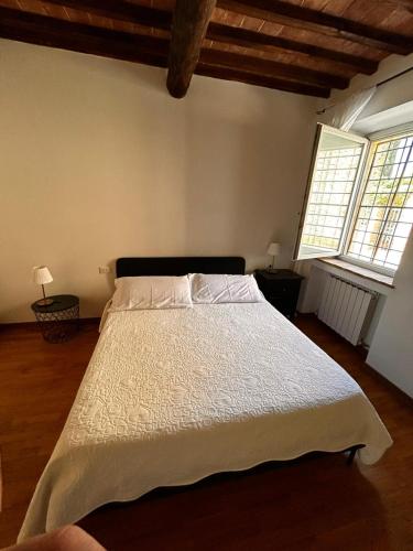 a bedroom with a large white bed with two windows at La Sosta Nel Chianti in Castelnuovo Berardenga