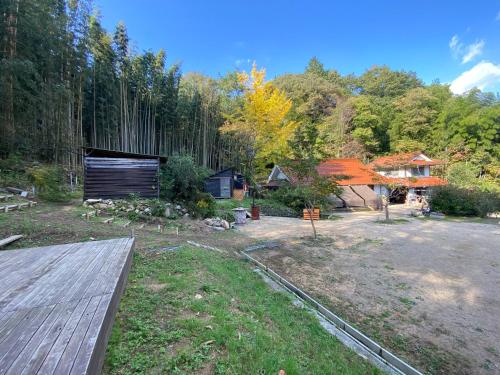 a yard with a wooden deck and a house at うさぎのキャンプ広場 in Oguni