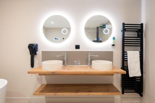 a bathroom with two sinks and two mirrors at Logis Hotel la Résidence in Le Val-dʼAjol