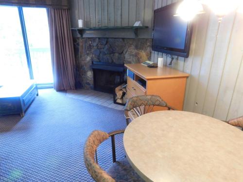 a room with a table and a tv and a fireplace at Douglas Fir Resort & Chalets in Banff