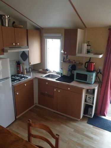 eine kleine Küche mit Spüle und Mikrowelle in der Unterkunft Petit logement tranquille in Wanchy-Capval
