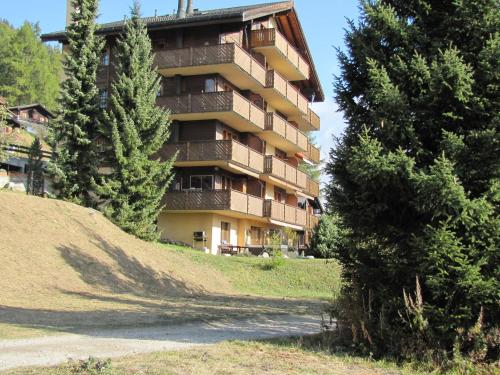 a tall apartment building on a hill with trees at Superb apartment with views of the Alps in Bellwald
