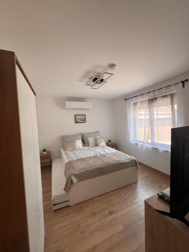 a white bedroom with a bed and a window at Tisza-tó Porta in Tiszafüred