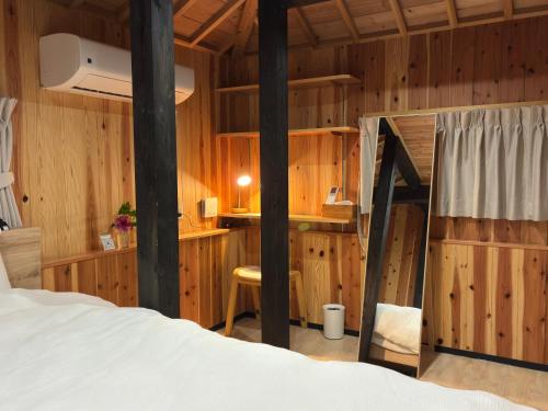 a bedroom with wooden walls and a bed in a room at 赤瓦のお宿みあげむい in Kunigami