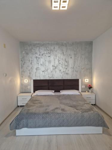a bedroom with a large bed and a concrete wall at Iris ultracentral apartment in Mangalia