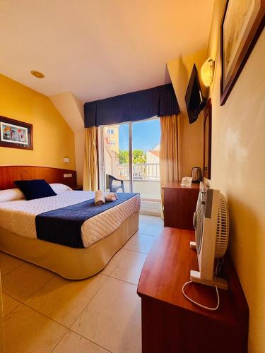 a bedroom with a bed and a television and a window at Hotel Atalaya II in Portonovo
