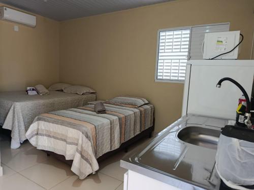 a small bedroom with two beds and a sink at Casa Studio Uirá - rua dos Cravos in Chapada dos Guimarães