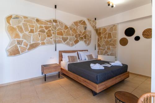 a bedroom with a king sized bed with a stone wall at GardenBlue By Gereoudis in Kolymvari