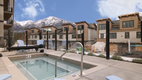 a swimming pool in front of a building with a mountain at Luxury Mountain Haven Views Hot Tub Central Bridgette Bar Main St in Canmore