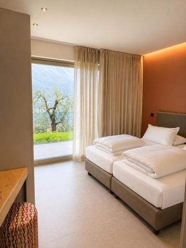 a bedroom with two beds and a large window at Eos Lake House Luxury in Limone sul Garda