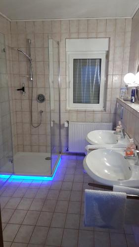 ein Badezimmer mit 2 Waschbecken und einer Dusche mit blauen Lichtern in der Unterkunft Gästezimmer Junglas in Bornheim