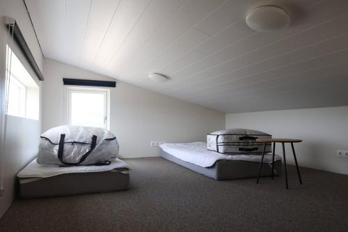 a bedroom with two beds and a table in it at Hvammur 10 with private hot tub in Kaldrananes