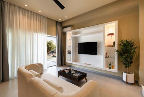 ein Wohnzimmer mit einem weißen Sofa und einem Fernseher in der Unterkunft Mitos Ultimate Escape Villa in Galanádhon